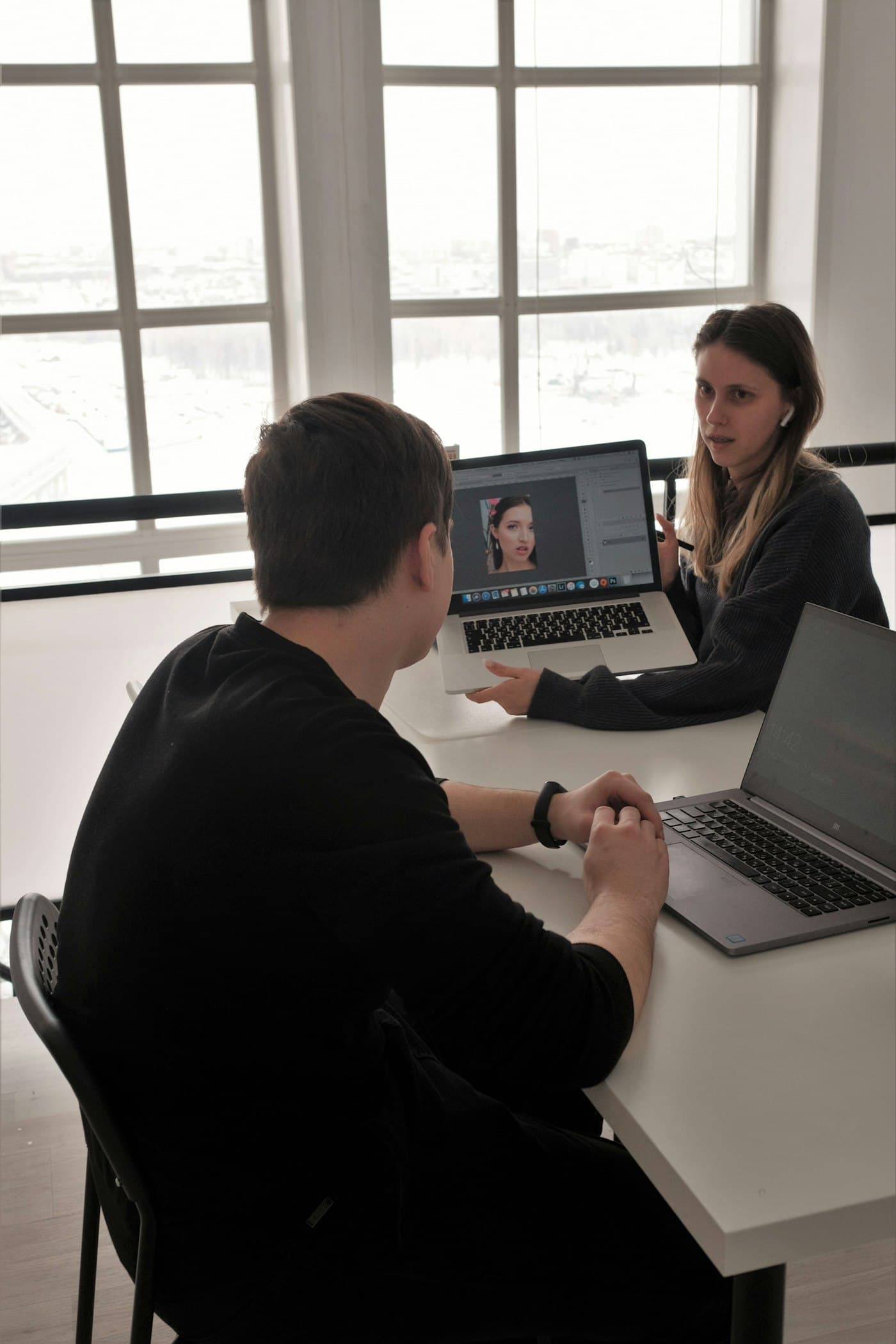 Two people talking through a plan over a laptop by a bright window